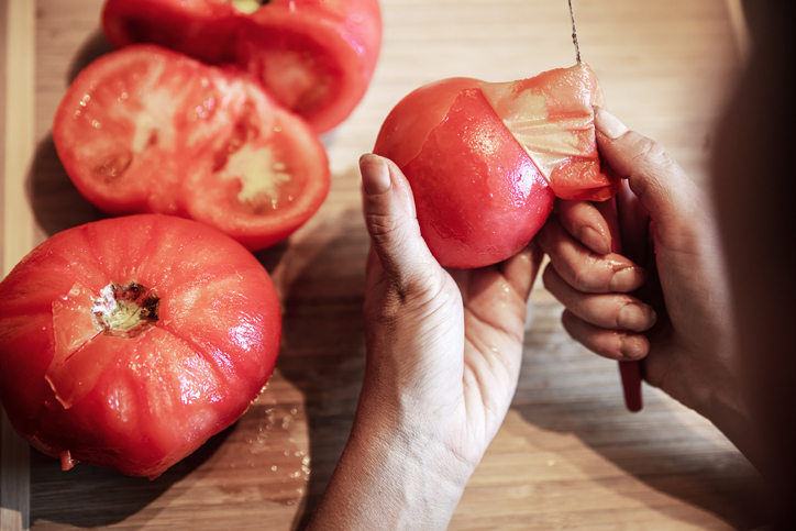 kobieta obiera pomidory ze skórki